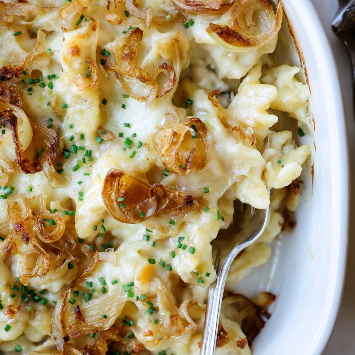 Ein appetitliches Foto von cremigem, gebackenem Käse-Spätzle, perfekt für ein gemütliches Abendessen.