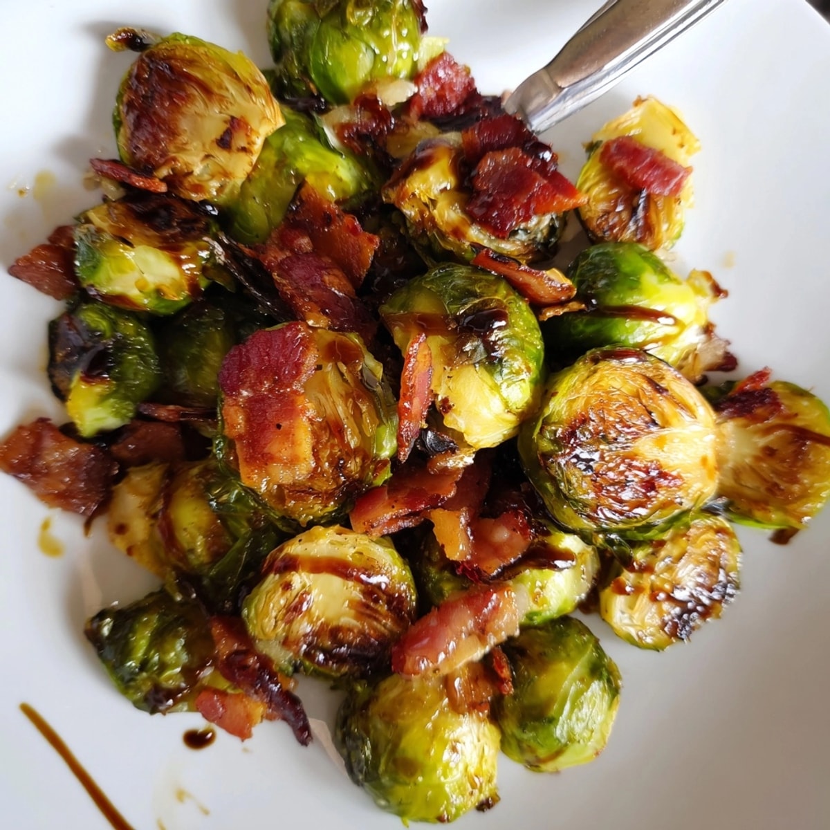 Eine Nahaufnahme von geröstetem Rosenkohl mit Speck; Balsamico-Glasur für eine süße Note.