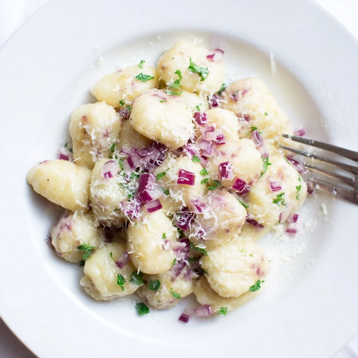 Plum Soda Gnocchi Bällchen in einer Buttersauce, garnierter mit frischen Pflaumenstücken.  