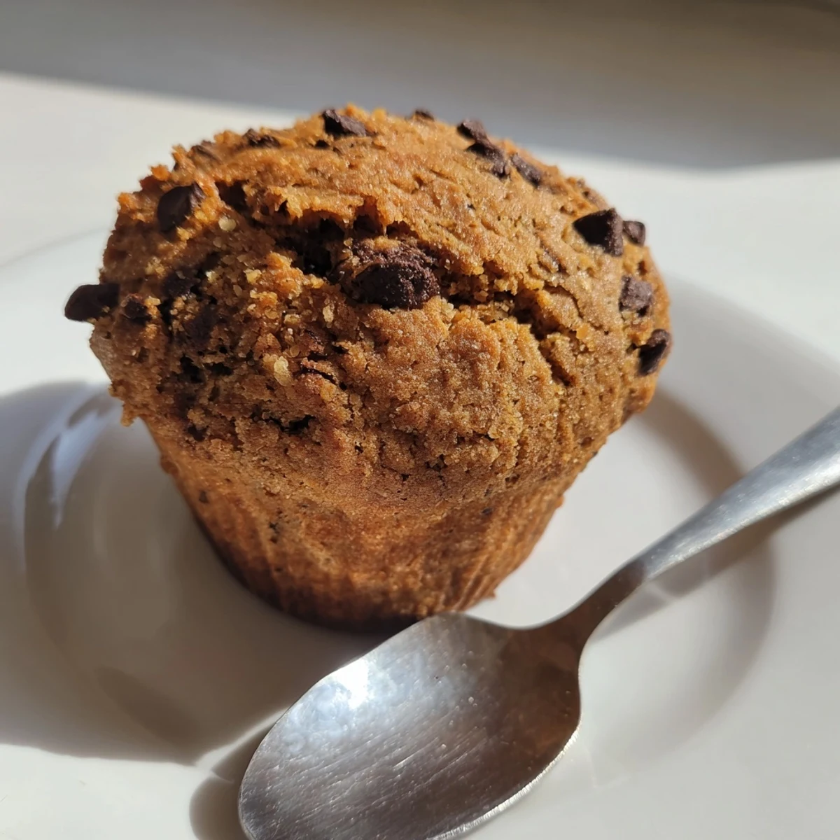 Freshly baked banana chocolate muffins, golden brown, with melted chocolate chips, ready to eat.