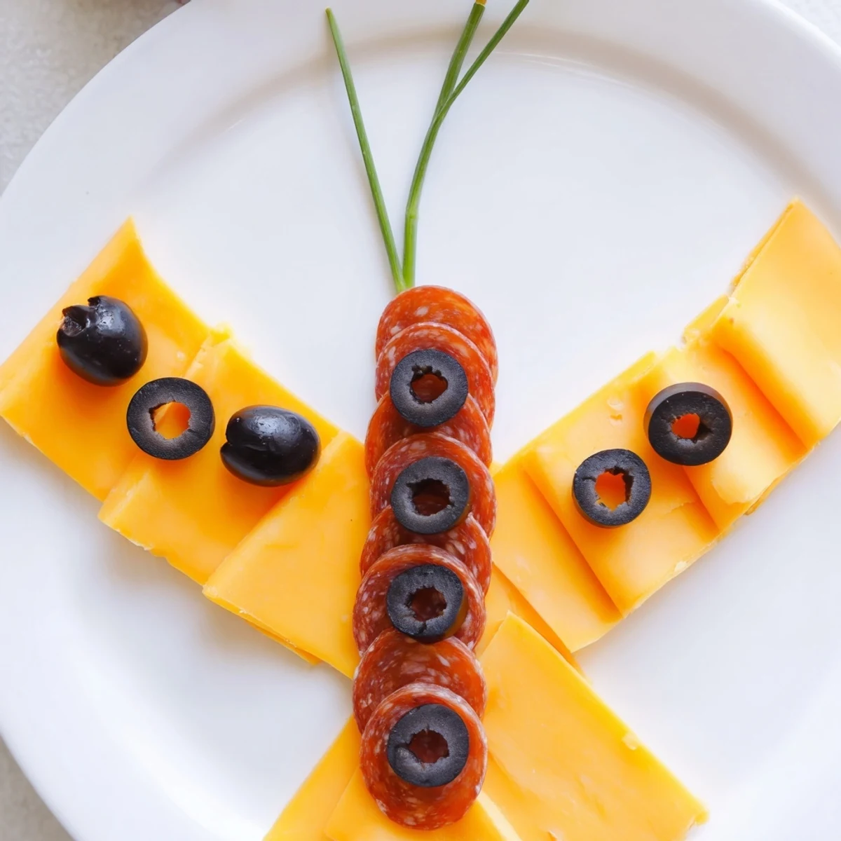Salami body and olive accents complete this creative Butterfly Migration appetizer; a fun, party-ready creation.