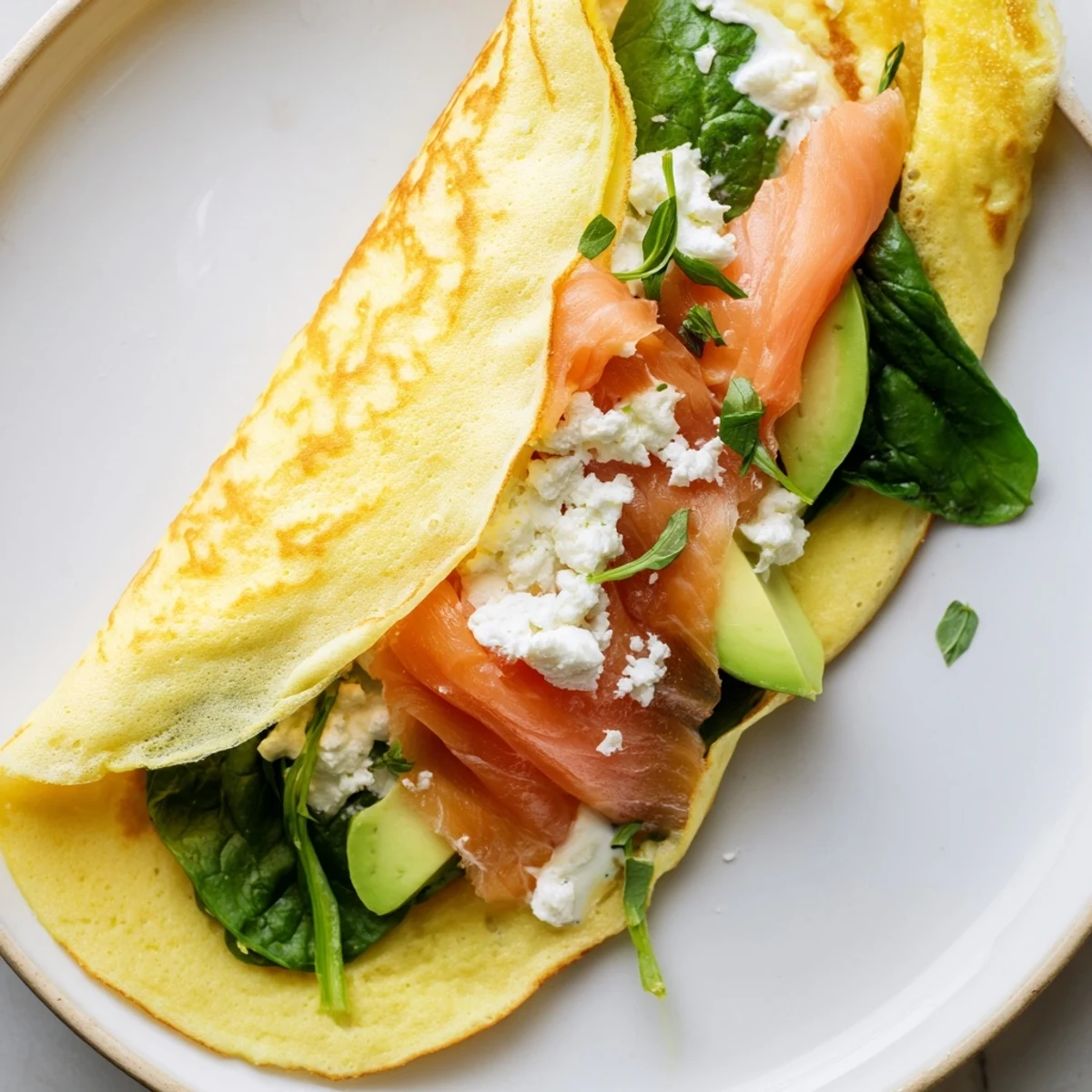 Golden, thin Blender-Egg Crepe Wrap filled with fresh spinach, salmon, and creamy avocado, ready to eat.