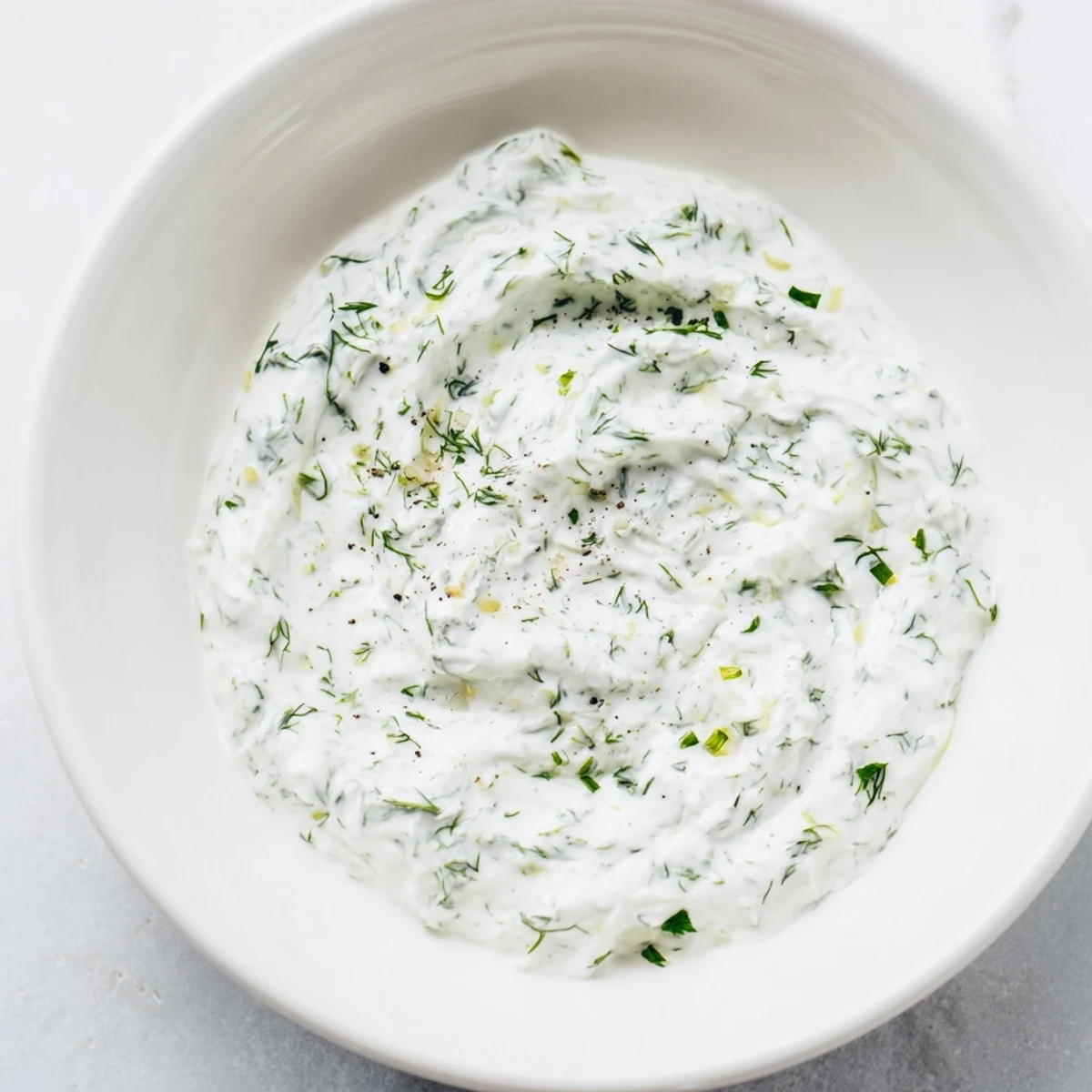 A bowl of creamy Greek yogurt herb dip with fresh herbs, ready for dipping vegetables.