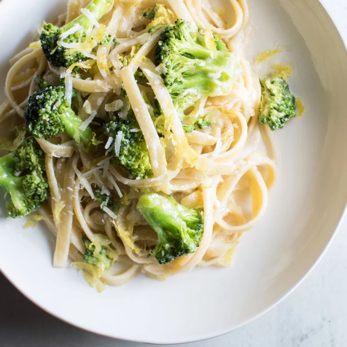 A steaming bowl of one-pot lemon broccoli pasta, garnished with fresh herbs and Parmesan.
