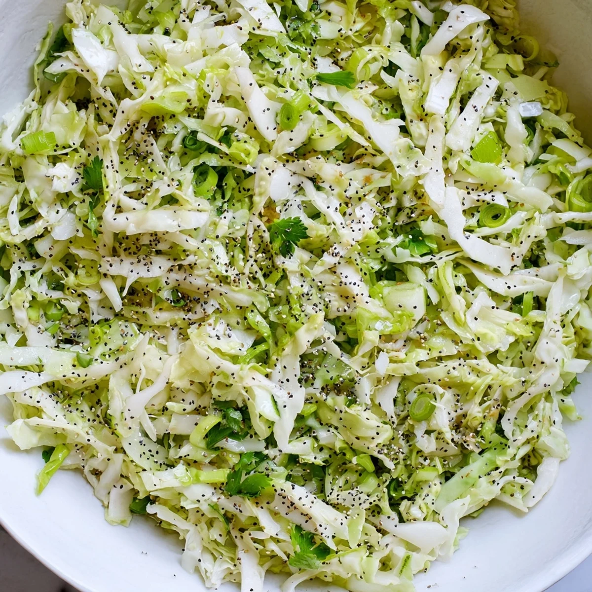 A close-up of vibrant green cabbage and apple slaw glistening with tangy dressing.