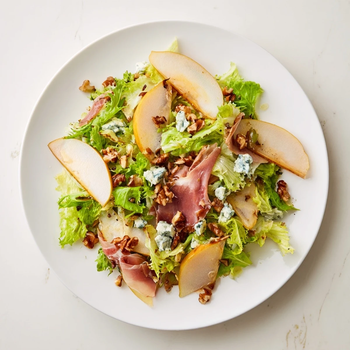 Gedünsteter Frisée, Birne, Blauschimmelkäse und knuspriger Prosciutto Salat auf einer rustikalen Holzplatte mit cremigem Blauschimmelkäse und golden knusprigen Prosciutto Streifen dargestellt.