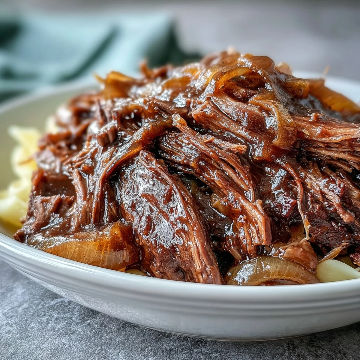 Tender shredded Crockpot French Onion Pot Roast Pasta with caramelized onions and buttery egg noodles ready to serve.