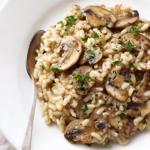 Cremiges Pilzrisotto mit Hefeflocken, ein dampfendes veganes Gericht dekoriert mit frischer Petersilie.