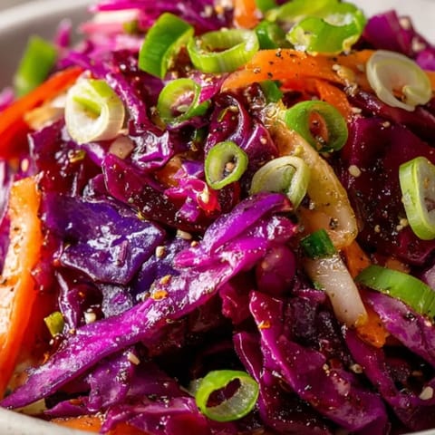 Frisch zubereiteter, einfacher roter Krautsalat mit Karotten und spritziger Vinaigrette, bereit zum Servieren als Topping.