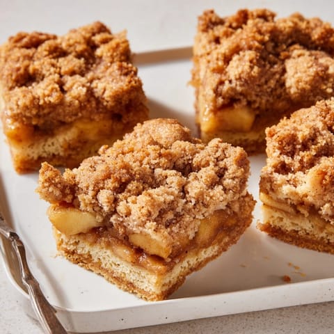 Goldbraune Dutch Apple Pie Squares, duftend nach Zimt und Äpfeln, servierbereit auf einer festlichen Tafel.