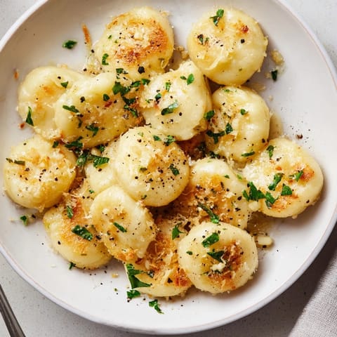 A steaming plate of potato dumplings with parmesan-garlic brown butter, ready to eat.