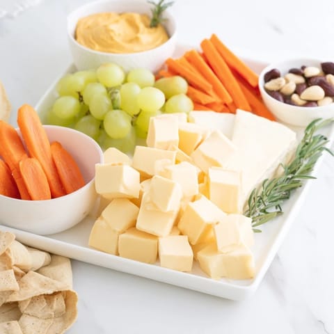 Vibrant Pumpkin Patch Snack Board: cheddar, gouda, and brie alongside fresh autumn treats.