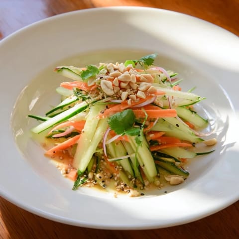 Close-up of a colorful Thai-Style Peanut Cucumber Salad with chopped peanuts sprinkled on top.