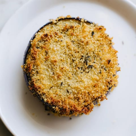 Enjoy a basket of savory Eggplant Parmesan Chips fresh from the oven, with a crispy breadcrumb coating.