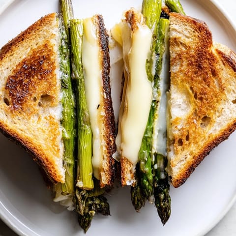 Luscious Asparagus & Brie Grilled Cheese on a plate, toasted bread showcasing creamy melted Brie cheese.