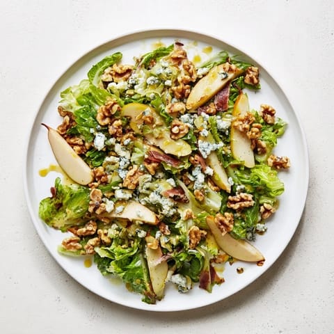 Eine frische Frisée, Birne, Blauschimmelkäse und knuspriger Prosciutto Salat Kombination mit saftigen Birnenscheiben und würziger Vinaigrette, perfekt für ein leichtes Mittagessen oder elegantes Vorspeisen.