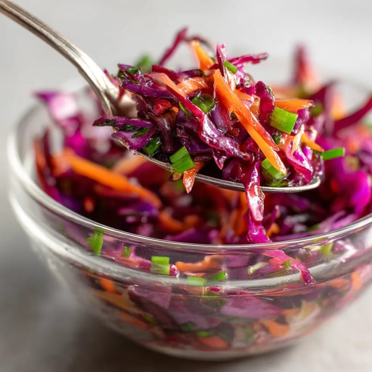 Ein Glas mit einer salzigen Beilage, die aus roten Kohl, Zwiebeln und einem Dressing aus Apfel und Zitronen besteht.