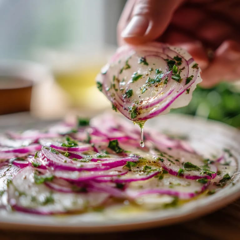 Ein Kohlrabi Carpaccio mit einem Zitronen-Dressing wird auf einem Teller präsentiert.