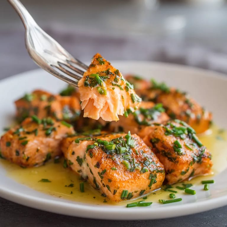 Ein weißer Teller mit Marinierter Lachs-Miniatur-Bissen und frischem Petersilie.