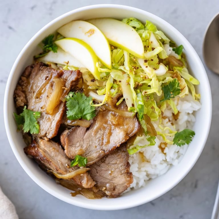 Herzhafter Apple and Cabbage Pork Bowl serviert auf dampfendem Reis.  