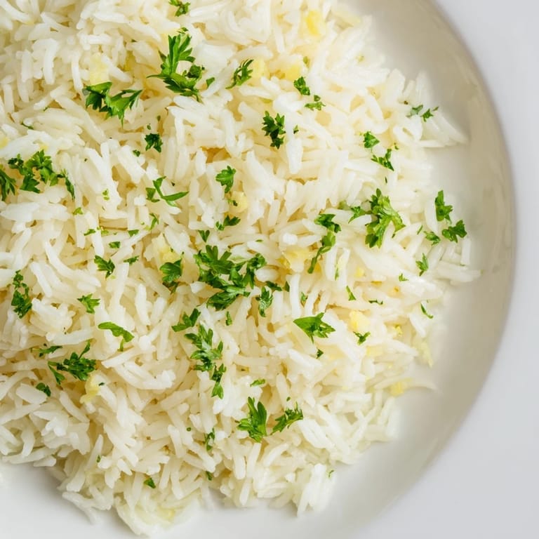 Close-up of golden-hued garlic butter rice, a flavorful side dish with fresh parsley garnish.